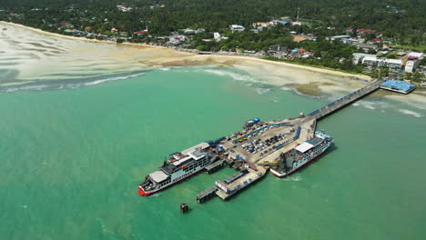 Aerial-tilt-down-shot-of-ferry-ship-at-nathon-pier-during-sunny-day-on-Koh-Samui,-Thailand