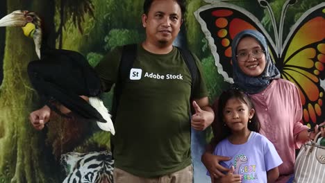A-family-poses-with-hornbills-at-Semarang-Zoo,-Indonesia