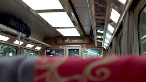 Static-shot-inside-japanese-train-with-travel-backpacks-laying-on-the-shelve-in-Osaka