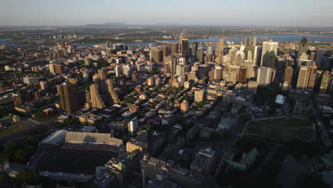 Aerial-view-away-from-the-sunlit-metropolis-of-Montreal,-summer-evening-in-Canada