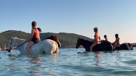 People-on-holiday-enjoy-riding-horse-in-sea-water-in-summer-season-in-Corsica,-France
