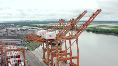 panoramic-shot-of-unloading-cargo-containers-in-a-port,-customs,-drone