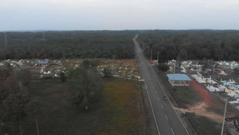 Flying-over-local-road-with-cemetery-at-Indonesia,-aerial