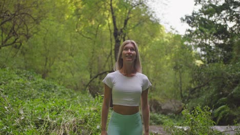 Blond-woman-looking-amazed-at-beauty-of-nature-in-lush-forest