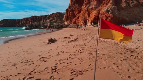 Red-and-yellow-flags-marking-the-swimming-area,-considered-safe-by-lifeguards,-Praia-Do-Tonel,-Sagres,-Portugal