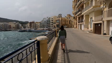 People-walking-on-coastal-street-of-Malta-cityscape,-POV