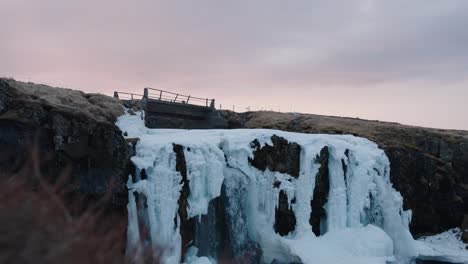 Frozen-Kirkjufellsfoss-waterfall-during-golden-hour-vibrant-sky,-Iceland