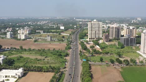 RAJKOT-CITY-AERIAL-VIEW-The-drone-camera-is-moving-over-Kalavad,-and-on-its-right-is-a-large-high-rise-building