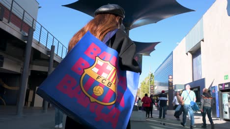 A-woman-holds-a-Barcelona-shopping-bag-as-fans-and-tourists-visit-Barcelona´s-football-stadium-facility,-Spotify-Camp-Nou,-and-its-official-merchandise-store