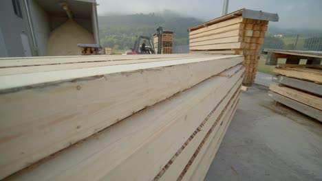 Overtake-Shot-Of-Wooden-Boards-Stocked-In-Construction-Site-Near-Forklift