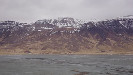 Slow-zoom-in-of-Iceland-volcanic-mountain-range-landscape-near-wet-meadow