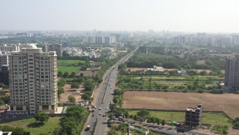 RAJKOT-CITY-AERIAL-VIEW-Drone-camera-moving-over-Kalavad-Road,-showing-many-high-rise-buildings-and-temples