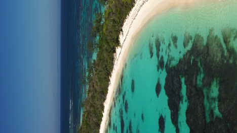 Remote-tropical-island-with-trees,-white-sand-beach,-New-Caledonia