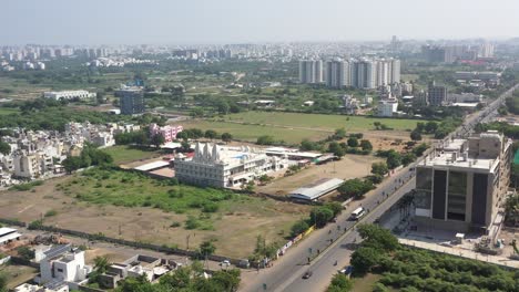 RAJKOT-CITY-AERIAL-VIEW-A-drone-is-moving-over-Kalavad-Road,-and-cows-and-buffaloes-are-seen-grazing-in-many-fields