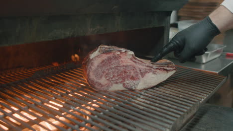 Chef-hand-places-Australian-dry-meat-steak-onto-a-hot-grill-in-restaurant-kitchen