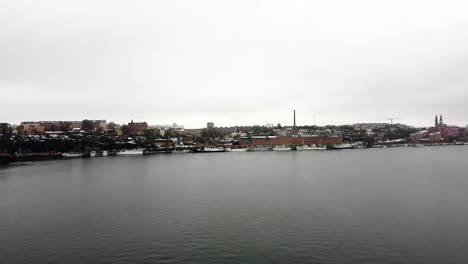Aerial-establishing-pan-of-Stockholm-Sweden-skyline-on-winter-day,-view-from-river