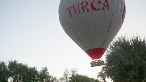 Turkish-Hot-air-balloons-flies-over-tree-tops-with-excited-tourist