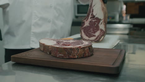 Chef-places-a-huge-slice-of-Australian-dry-beef-meat-steak-slice-onto-wooden-cutting-board