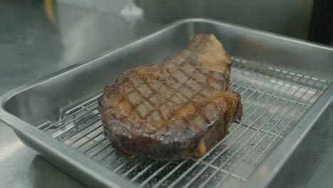 Close-up-on-a-grilled-Australian-dry-beef-meat-into-metal-tray-on-restaurant-kitchen-table