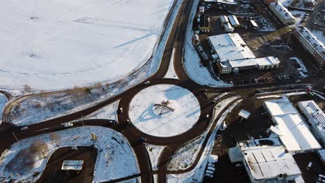 Red-horse-stands-out-in-middle-of-snow-covered-roundabout-at-midday-in-Sweden