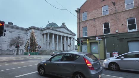 Street-Cork-city-with-Courthouse-and-double-decker-buses,-a-decorated-Christmas-tree-in-the-evening