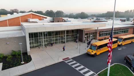 Estudiantes-Que-Llegan-A-La-Escuela-Secundaria-Americana-En-Autobuses-Escolares-Amarillos