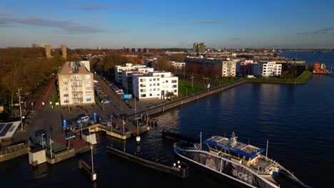 Ferry-arriving-at-Amsterdam-Noord-IJplein-on-sunny-day-drone-orbit