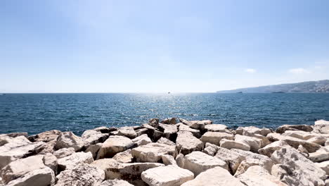 Bright-day-over-calm-sea-and-rocky-shoreline-in-Sorento,-Italy