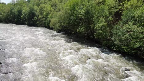Drohnenansicht-In-Albanien,-Die-An-Einem-Sonnigen-Tag-über-Einen-Fließenden-Stromschnellenfluss-Zwischen-Grünen-Bergen-Fliegt