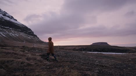 Man-walk-on-volcanic-landscape-near-mountain-during-golden-hour,-Iceland