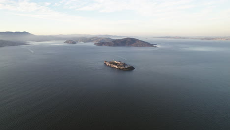 Aerial-view-approaching-the-Alcatraz-prison,-sunset-in-San-Francisco,-USA