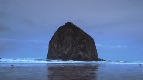 Timelapse-of-a-moody-Cannon-Beach-with-low-fog-and-waves-crashing-with-a-few-seagulls-hanging-around-the-sand