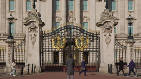 Un-Hombre-De-Pie-Junto-Con-Un-Transeúnte-Frente-Al-Palacio-De-Buckingham,-Londres,-Reino-Unido.