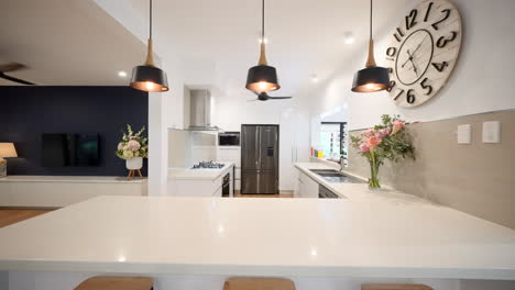 Anspruchsvolle-Küche:-Kiefernholzdielen,-Weiße-Steinplatten,-Stilvolle-Schwarze-Hängelampen,-Barhocker,-Moderne-Geräte