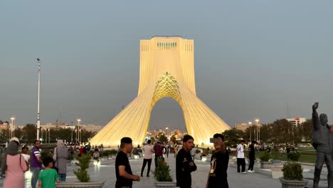 Menschen-Gehen-Durch-Teheran,-Den-Iranischen-Azadi-Shahyad-Turm-Auf-Dem-Platz-Der-Freiheit,-Und-Ein-Auswanderer-Führt-Einen-Videoanruf-Mit-Seiner-Familie-Im-Stadtzentrum-Im-Nahen-Osten,-Asien.-Touristen-Besuchen-Am-Wochenende-Eine-Wahrzeichenattraktion
