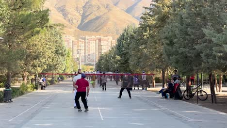 Iranische-Männer-Spielen-Im-Park-Badmintonnetz-Und-Vegetation-Landschaftsdesign-Menschen-Am-Frühen-Morgen-Trainieren-Malerische-Aussicht-Auf-Teheran-Iran-Bergsonne-Scheint-Saubere-Luft-In-Der-Sommersaison-Wochenendleben
