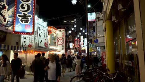 Gente-Caminando-En-La-Zona-De-Shinsekai,-Calle-Muy-Transitada-En-Osaka-Durante-La-Noche