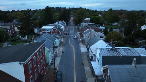 Twilight-over-a-quiet,-small-town-street-lined-with-traditional-houses-and-cars