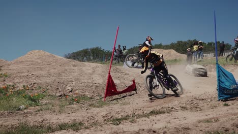 Ciclistas-De-Montaña-A-La-Deriva-Sobre-La-Polvorienta-Carrera-De-Obstáculos,-Cámara-Lenta-De-Mano