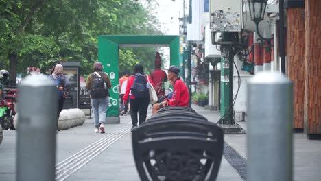 Ein-Erwachsener-Mann-Sitzt-Allein-Auf-Der-Bank-Am-Straßenrand-Inmitten-Des-Geschäftigen-Treibens-Der-Passanten