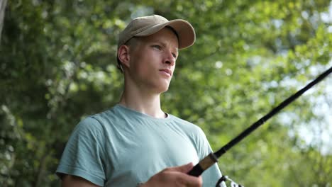 Male-angler-gets-fishing-rod-out-surrounded-by-trees-on-sunny-day,-close-up