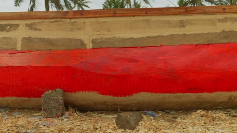 Schwarzer-Männlicher-Arbeiter-Malt-In-Rot-Ein-Traditionelles-Afrikanisches-Fischerboot-Aus-Holz