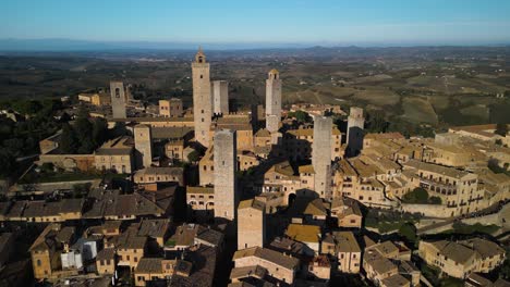 Toma-De-Cierre-Cinematográfica:-Un-Dron-Se-Aleja-Volando-De-Las-Torres-Medievales-En-San-Gimignano,-Italia.