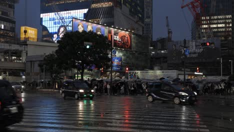 Shibuya-Scramble-Square-Cruzando-El-Tráfico-Por-La-Noche-Durante-La-Lluvia,-Tokio,-Japón
