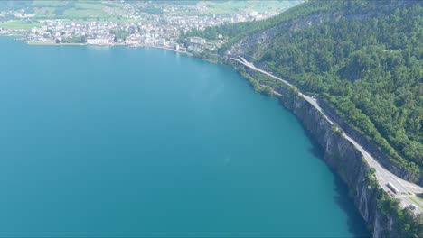 Morschach-Flyover:-Moving-Over-Scenic-Water-Valley-Towards-Alps-Mountains,-Switzerland,-Europe,-Drone-|-Inland-Movement-Along-Road-Cliffside-Beside-Majestic-Blue-Lake