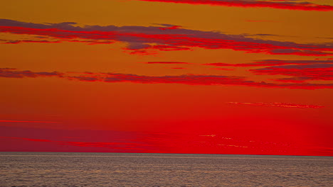 Time-lapse-shot-of-deep-red-and-orange-sunset-over-a-calm-sea