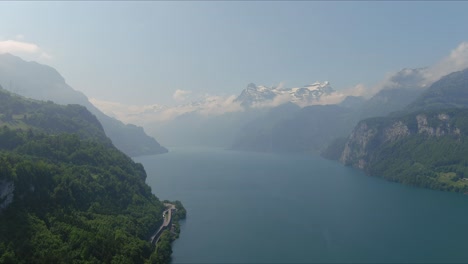Paso-Elevado-De-Morschach:-Moviéndose-Sobre-El-Pintoresco-Valle-De-Agua-Hacia-Las-Montañas-De-Los-Alpes,-Suiza,-Europa,-Drone-|-Movimiento-Hacia-El-Interior-A-Lo-Largo-De-La-Ladera-Hasta-El-Vasto-Y-Majestuoso-Lago-Azul.