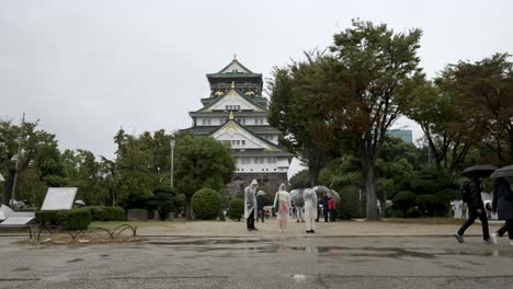 Gente-Caminando-Por-Los-Jardines-Frente-Al-Castillo-De-Osaka-Durante-Un-Día-Lluvioso