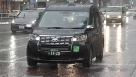 Tráfico-Por-Carretera-En-El-Centro-De-La-Ciudad-Y-Viajeros-Durante-Las-Fuertes-Lluvias,-Kabukicho,-Shinjuku,-Tokio,-Japón