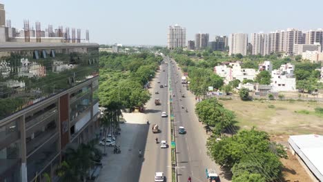 RAJKOT-CITY-AERIAL-VIEW-Drone-camera-flying-between-Kalawad-Road-in-Rajkot-surrounded-by-large-deciduous-trees